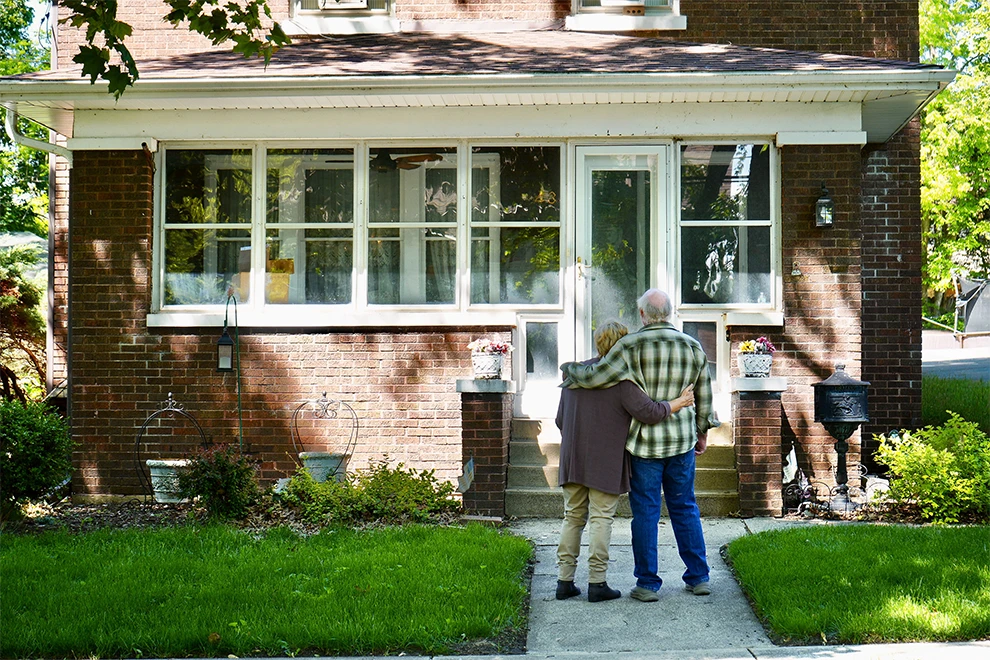 Older couple outside their home before downsizing