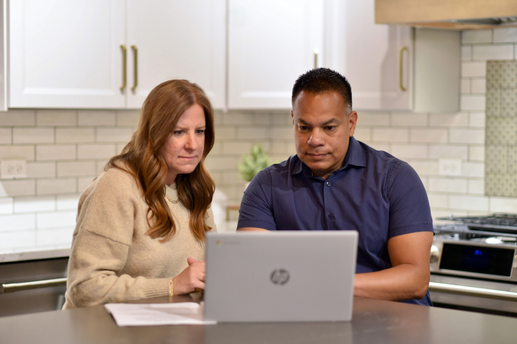 Two people reviewing information on a laptop while exploring options for selling an inherited house.